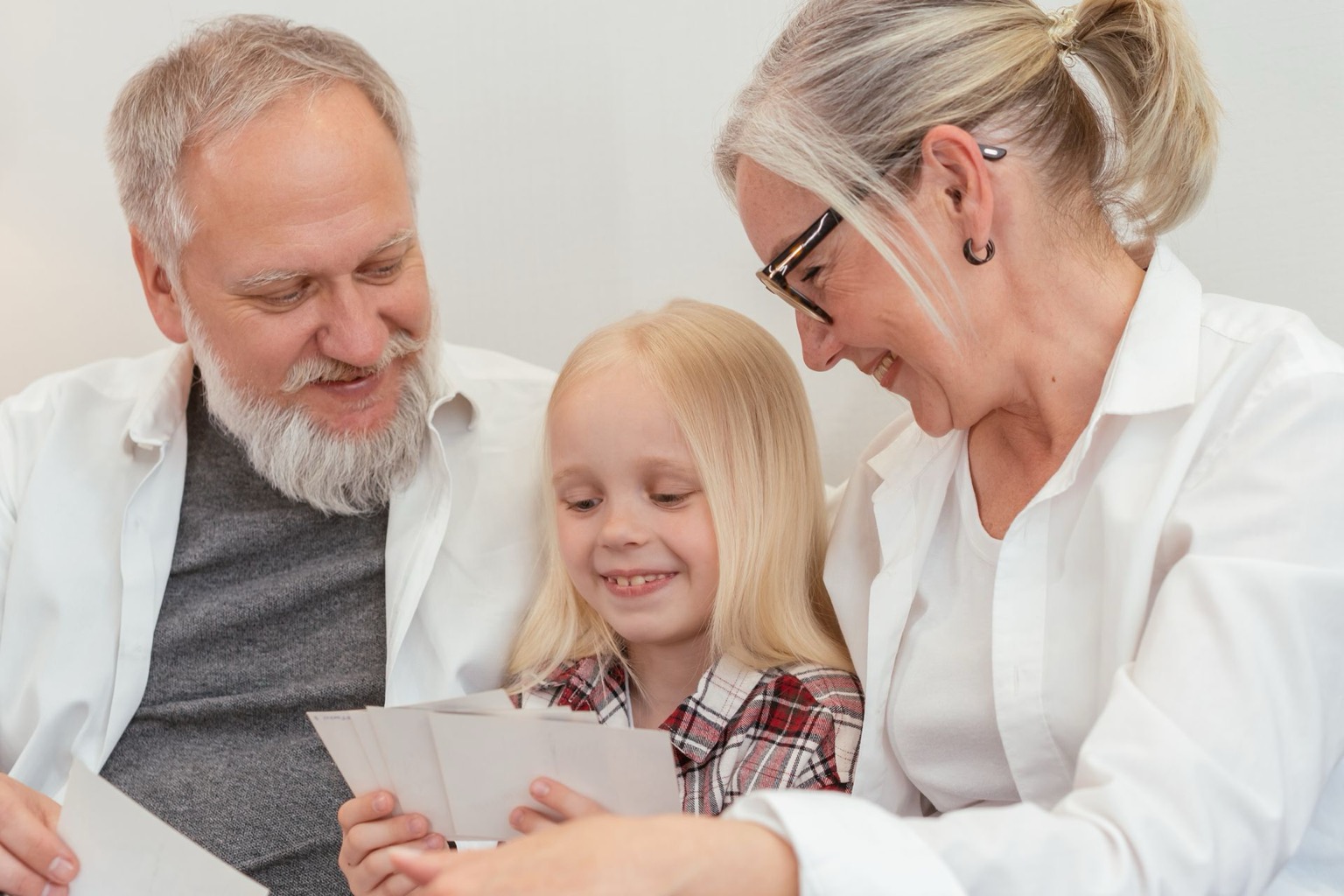 Symbolisches Stockfoto: Großeltern und Enkelin betrachten gemeinsam Familienfotos