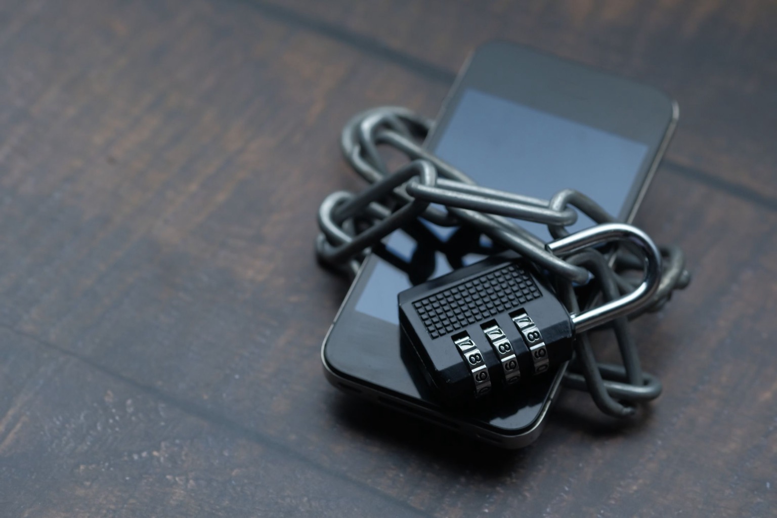 Symbolisches Stockfoto: Ein Smartphone ist mit Kette und Zahlenschloss gesichert.