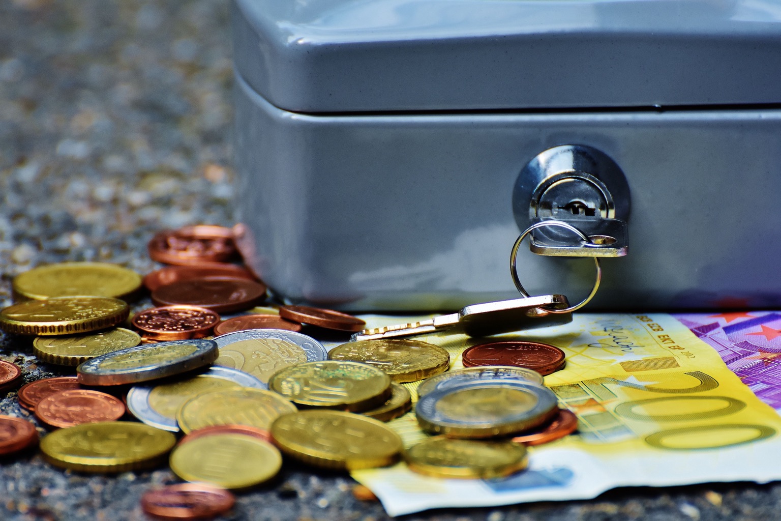 Symbolisches Stockfoto: Verschlossene Geldkassette mit Euro-Bargeld und Schlüssel.