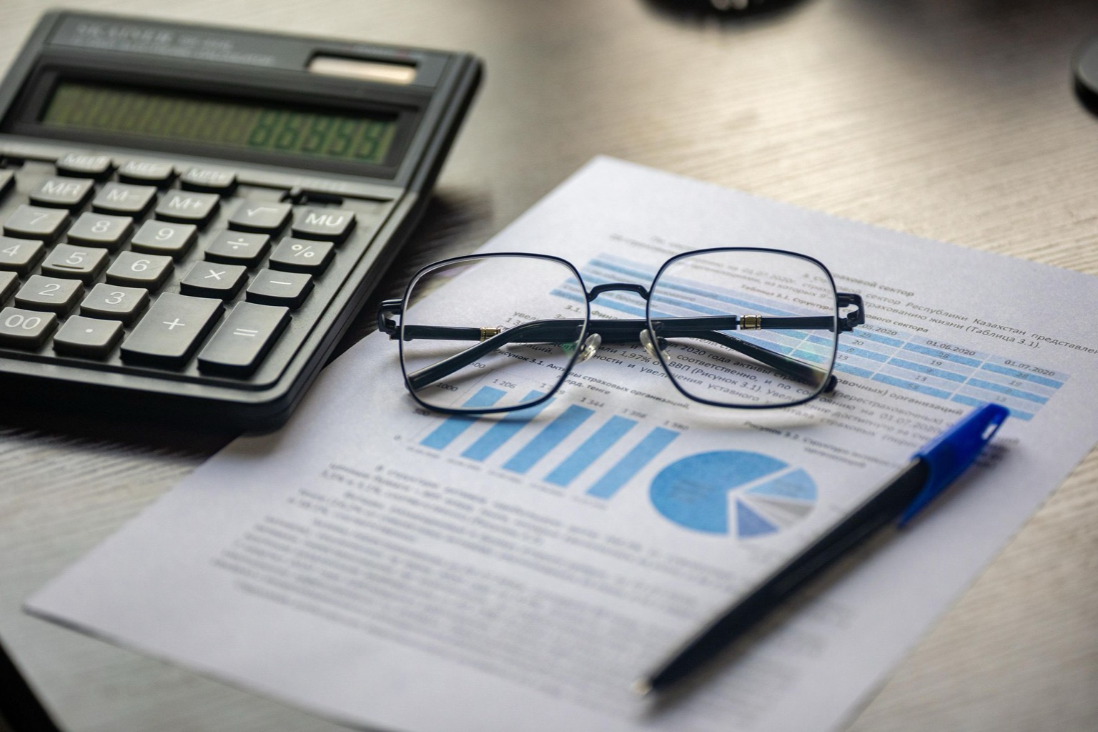 Symbolisches Stockfoto: Finanzunterlagen mit Taschenrechner, Brille und Diagrammen.