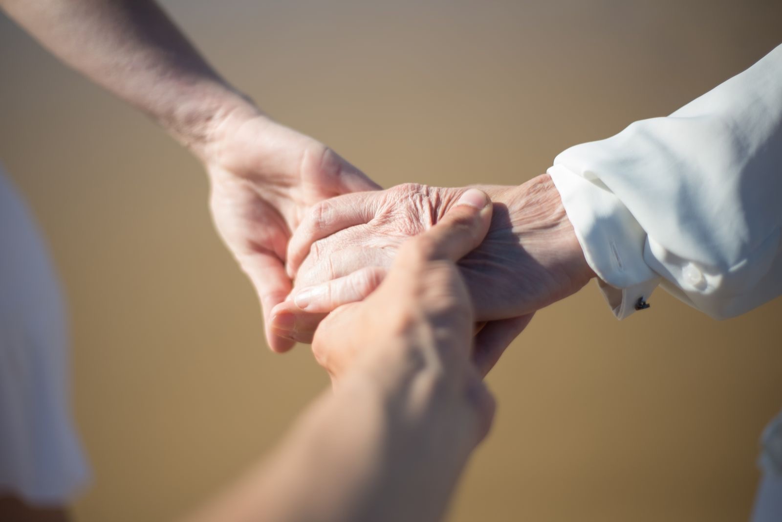 Symbolfoto: Jüngere Hände halten behutsam die Hand einer älteren Person.